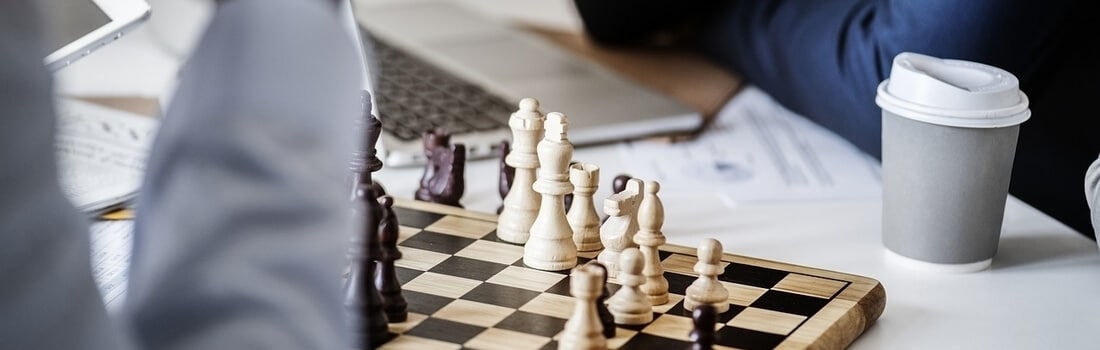 tablero de ajedrez y laptop donde se investiga hasta qué edad se paga pensión alimenticia
